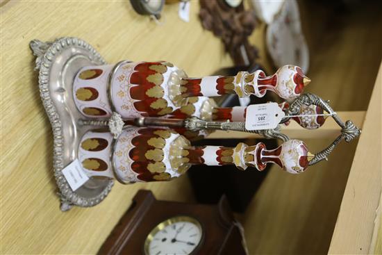 A plated three bottle tantalus, the decanters overlaid glass with gilt decoration, height 37cm